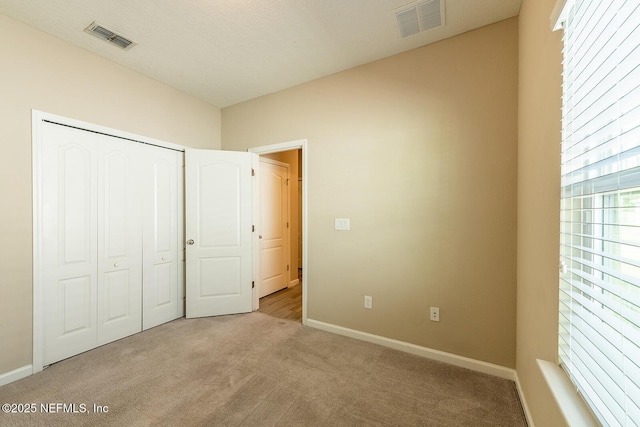 unfurnished bedroom with light colored carpet and a closet