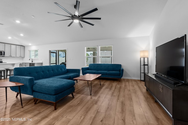 living room featuring plenty of natural light, vaulted ceiling, and light wood-type flooring