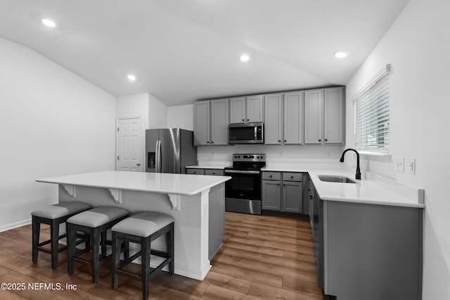 kitchen with lofted ceiling, sink, a center island, a kitchen breakfast bar, and stainless steel appliances