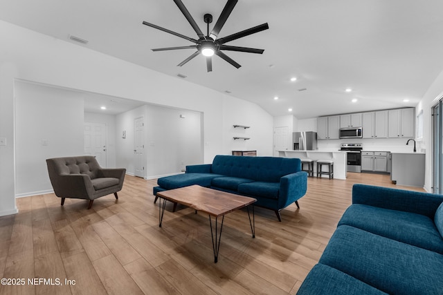 living room with vaulted ceiling, sink, ceiling fan, and light hardwood / wood-style flooring