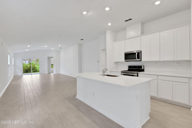 348 Salazar St, Saint Augustine, FL 32095 - kitchen featuring stainless steel appliances, recessed lighting, a center island with sink, light wood finished floors, and white cabinets