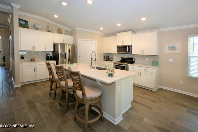 kitchen with sink, stainless steel appliances, an island with sink, and white cabinets