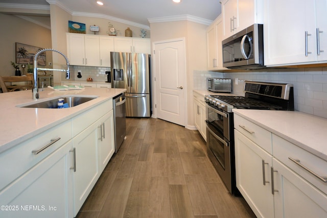 kitchen featuring stainless steel appliances, white cabinetry, sink, and light hardwood / wood-style floors