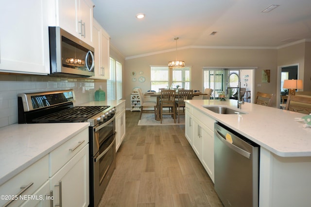 kitchen featuring sink, white cabinetry, hanging light fixtures, stainless steel appliances, and a kitchen island with sink