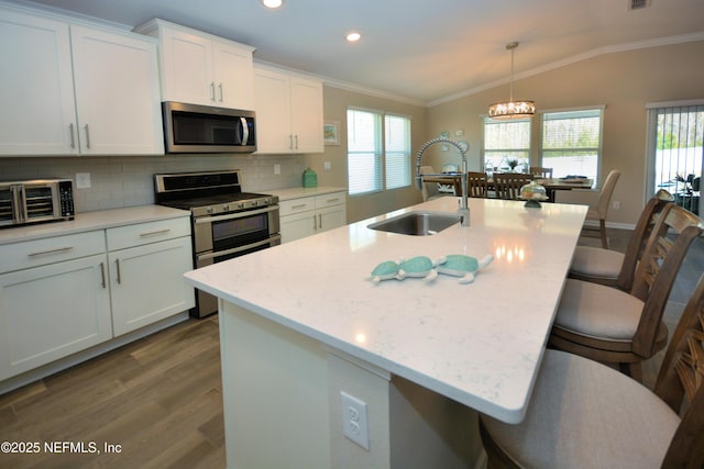 kitchen with appliances with stainless steel finishes, sink, a center island with sink, and decorative light fixtures