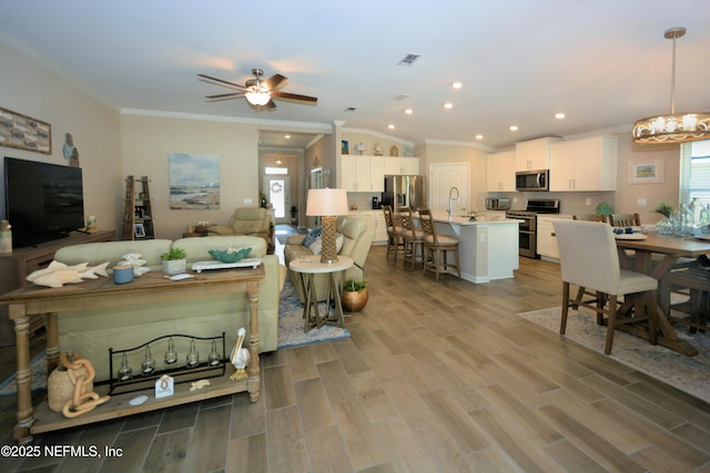 living room featuring sink, crown molding, a wealth of natural light, and light wood-type flooring