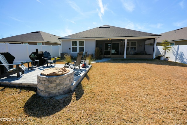 rear view of house with a patio, a sunroom, a yard, and a fire pit