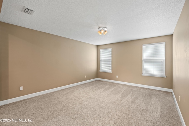 carpeted empty room featuring a textured ceiling