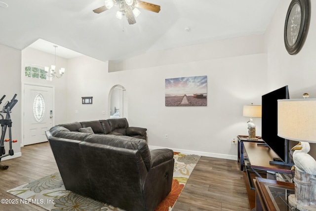 living area featuring baseboards, arched walkways, wood finished floors, high vaulted ceiling, and ceiling fan with notable chandelier