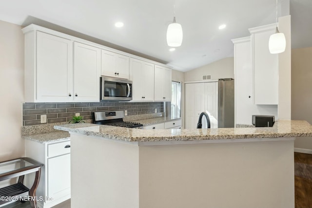 kitchen with a peninsula, white cabinetry, appliances with stainless steel finishes, and light stone counters