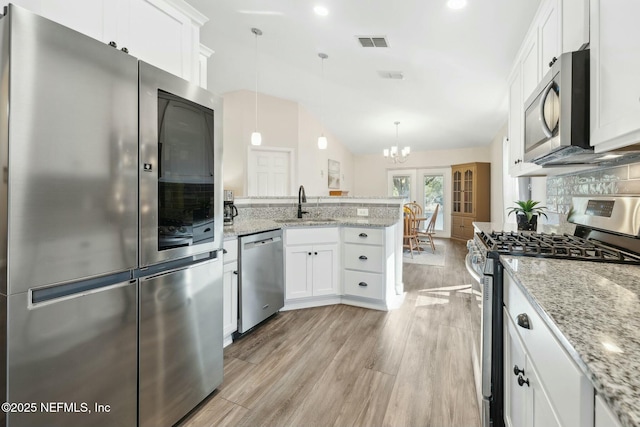 kitchen featuring appliances with stainless steel finishes, pendant lighting, white cabinets, and a sink