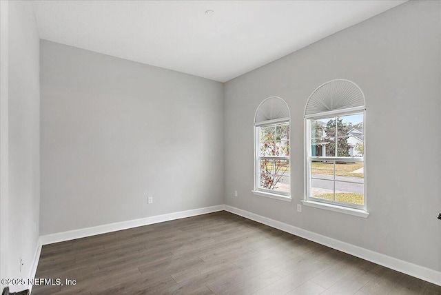 spare room featuring dark wood-style floors and baseboards