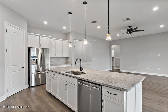 kitchen with stainless steel appliances, a sink, visible vents, white cabinetry, and an island with sink