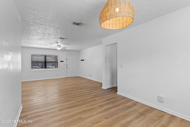 unfurnished room featuring visible vents, light wood-style flooring, a textured ceiling, and baseboards