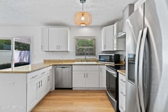 kitchen with backsplash, a peninsula, appliances with stainless steel finishes, and a sink