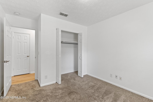unfurnished bedroom featuring baseboards, carpet, a textured ceiling, and visible vents