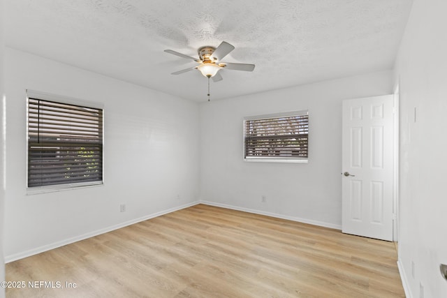 empty room with a textured ceiling, baseboards, a ceiling fan, and light wood-style flooring