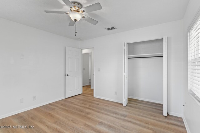 unfurnished bedroom featuring baseboards, visible vents, light wood-style flooring, and a closet