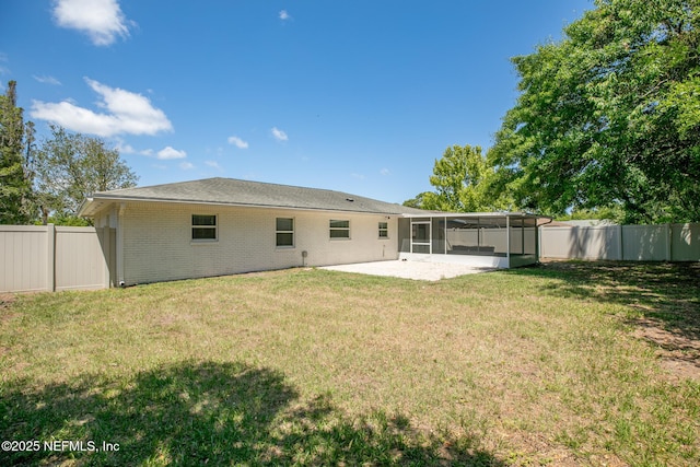 back of property featuring a patio area, a sunroom, brick siding, a fenced backyard, and a yard