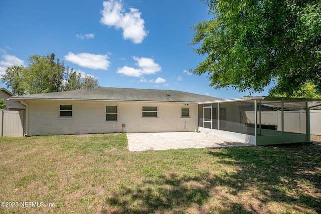 rear view of property with a patio area, a sunroom, brick siding, fence, and a yard