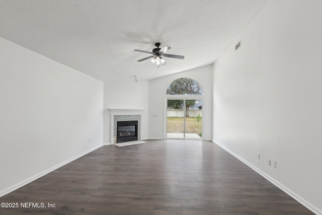 unfurnished living room with lofted ceiling, dark wood-type flooring, ceiling fan, a textured ceiling, and a tiled fireplace