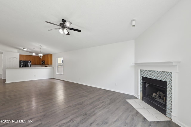 unfurnished living room with ceiling fan, vaulted ceiling, light wood-type flooring, and a fireplace