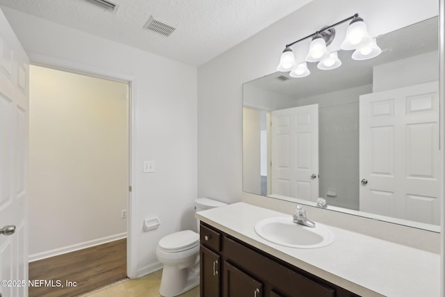 bathroom featuring vanity, hardwood / wood-style flooring, toilet, and a textured ceiling