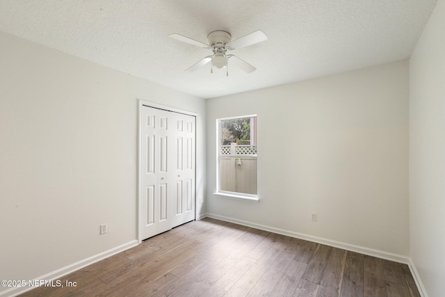 unfurnished bedroom with ceiling fan, hardwood / wood-style floors, a textured ceiling, and a closet