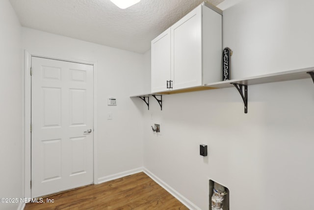 laundry area featuring cabinets, washer hookup, light hardwood / wood-style floors, and a textured ceiling