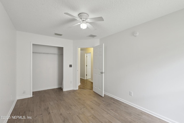 unfurnished bedroom with ceiling fan, light hardwood / wood-style floors, a closet, and a textured ceiling