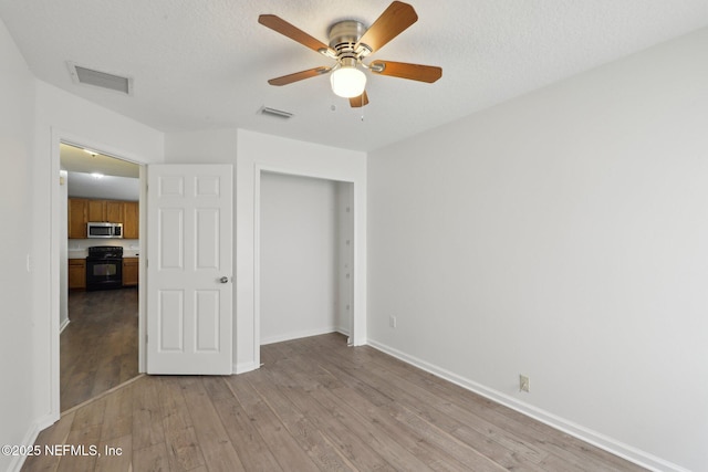 unfurnished bedroom featuring ceiling fan, a textured ceiling, light wood-type flooring, and a closet