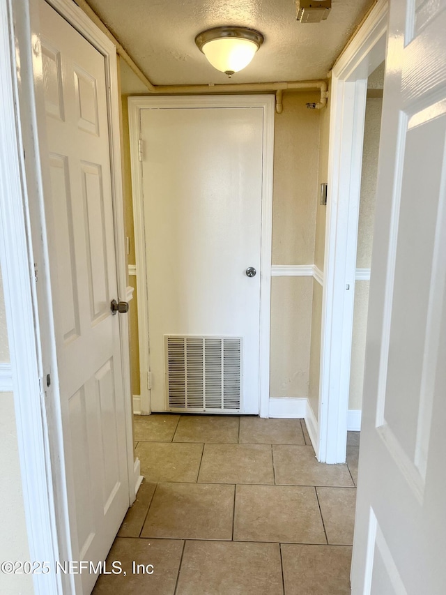 hallway with light tile patterned floors and a textured ceiling