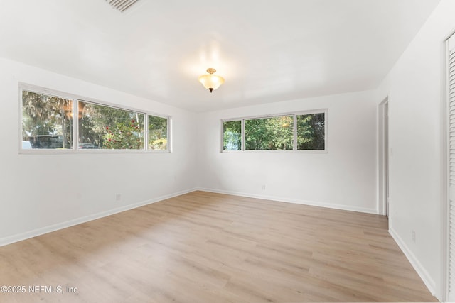 unfurnished room featuring light wood finished floors, visible vents, and baseboards