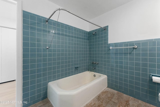 bathroom featuring wainscoting, tile walls, and shower / bathtub combination