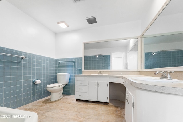 full bathroom featuring a shower, toilet, a wainscoted wall, vanity, and tile walls