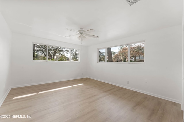 spare room featuring a ceiling fan, light wood-type flooring, visible vents, and baseboards