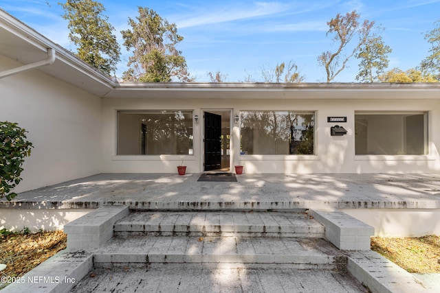 property entrance featuring a patio and stucco siding