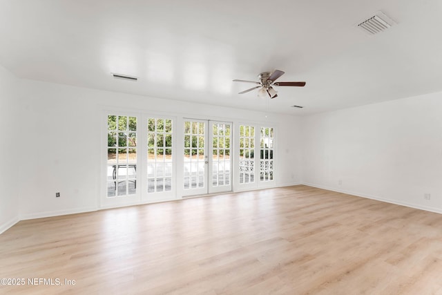 spare room featuring a wealth of natural light, visible vents, and light wood-style floors