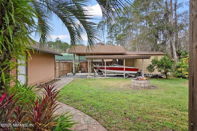 back of property with a yard, a fire pit, and fence