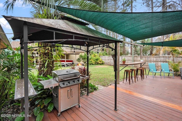 wooden terrace featuring a fenced backyard, a lawn, a gazebo, and area for grilling