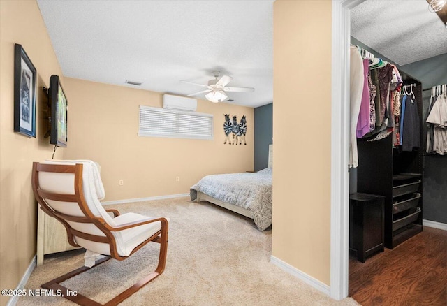 bedroom featuring baseboards, visible vents, a wall unit AC, carpet, and a spacious closet