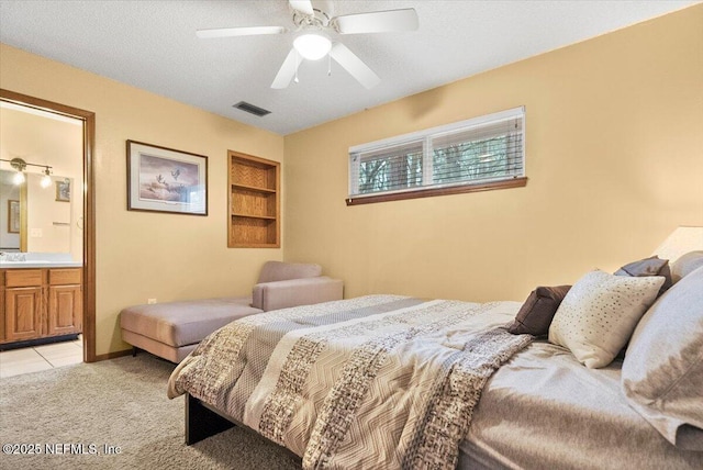 bedroom with visible vents, connected bathroom, light colored carpet, ceiling fan, and a textured ceiling