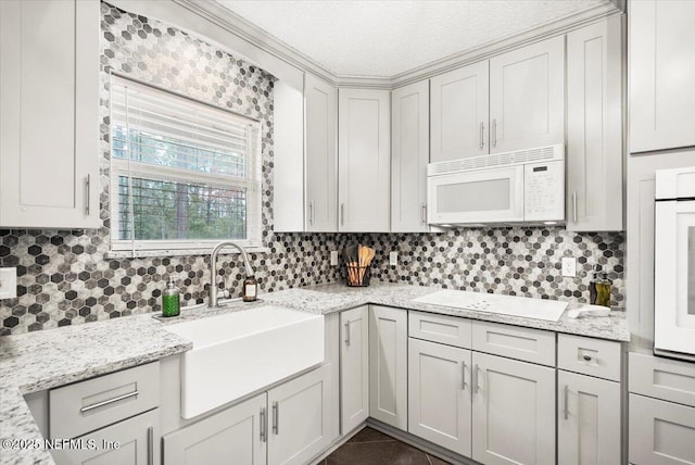 kitchen featuring light stone counters, white appliances, and a sink