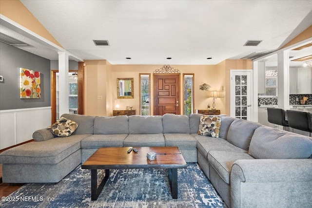 living room with dark wood-style floors, wainscoting, and visible vents