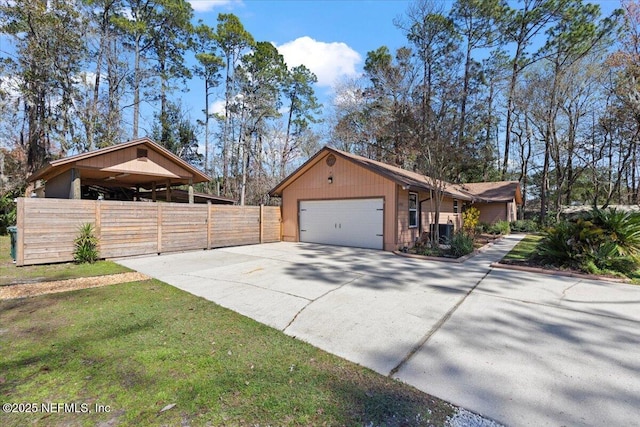 view of side of property with central air condition unit, a lawn, an attached garage, fence, and driveway