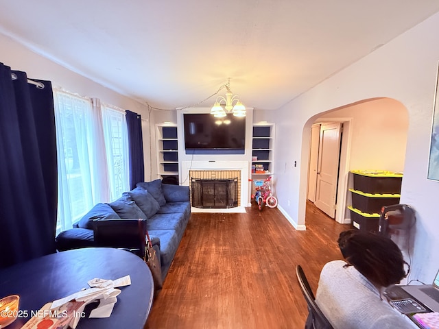 living room featuring hardwood / wood-style flooring, lofted ceiling, an inviting chandelier, and a fireplace