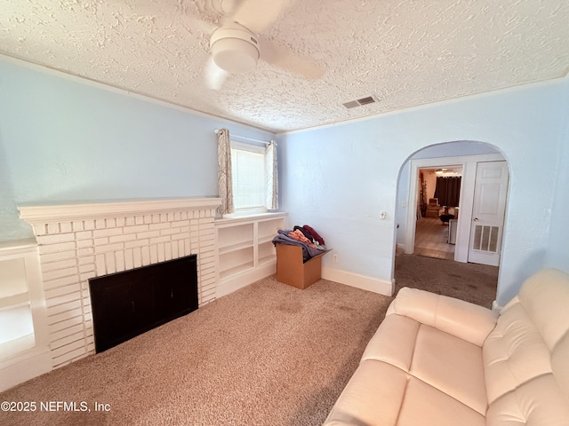 living room featuring a brick fireplace, carpet, and a textured ceiling