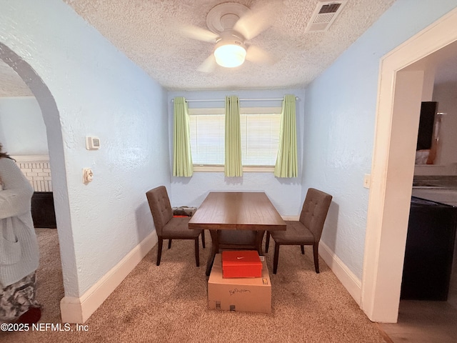 dining room with ceiling fan, light colored carpet, and a textured ceiling