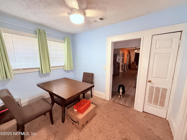 carpeted dining area featuring ceiling fan and a textured ceiling