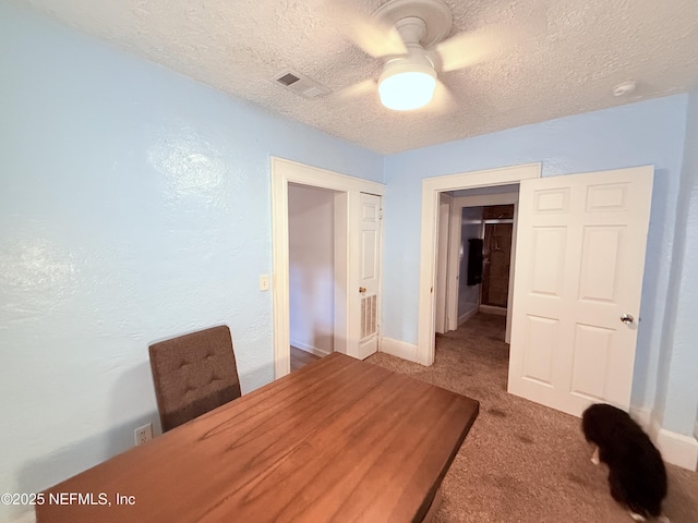 interior space featuring ceiling fan, carpet floors, and a textured ceiling